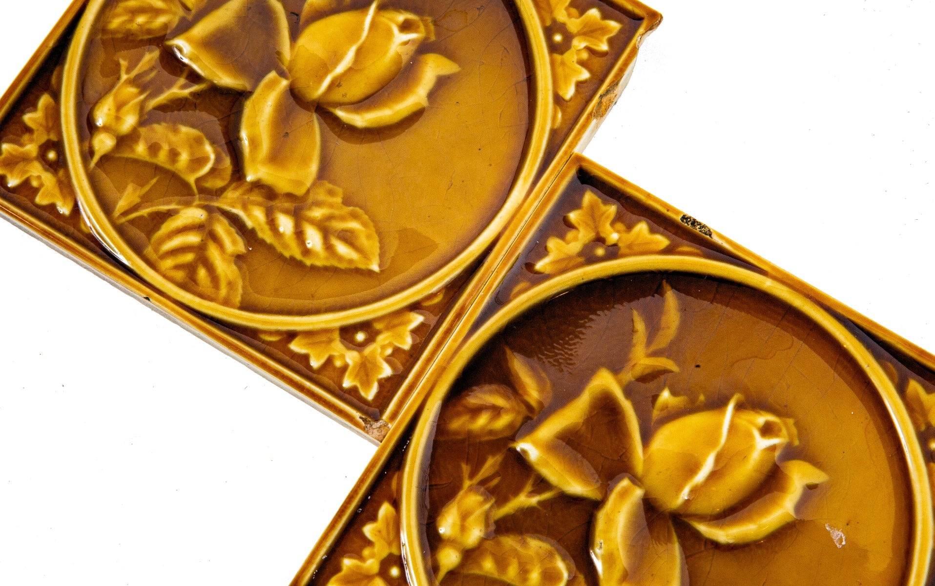 two matching 19th century butterscotch-colored encircled floral motif 6 x 6 fireplace mantel corner tiles