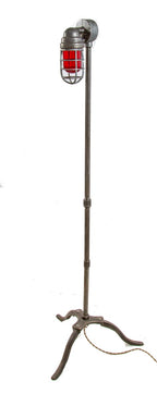 repurposed brushed steel pipe floor lamp with three-legged cast iron base and ruby red explosion proof bulb guard