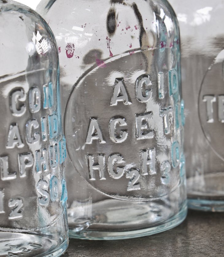 group of four original and intact matching clear glass american industrial research chemistry laboratory reagent bottles with intact circular-shaped tapered ground glass stoppers